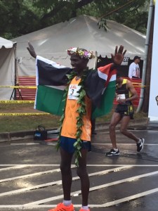 Champion's pose as fifth-place finisher and pre-race co-favorite Yemane Adhane of Ethiopia suffers in the background.