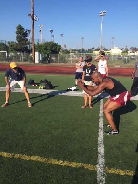 Nathaniel McBride loads up for the standing broad jump as University High School XC coach Gimi McCarthy prepares to measure the mark.